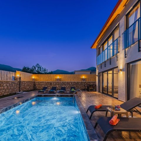 Luxurious villa with pool lit at twilight, available with a booking deposit